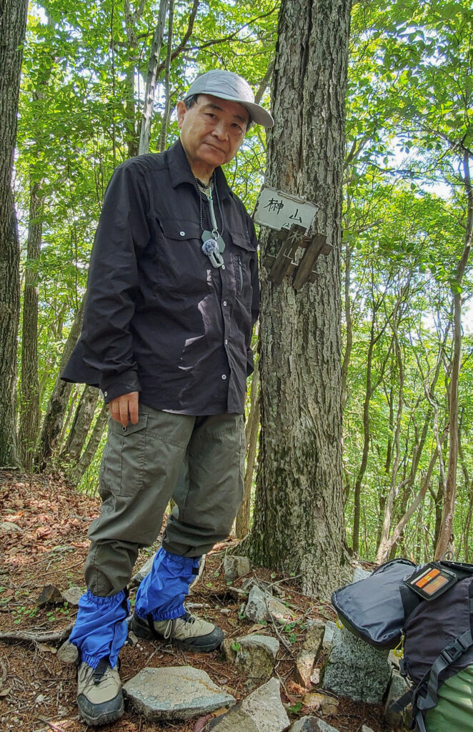 長野県佐久市の榊山山頂で山名標識の横に立つShin