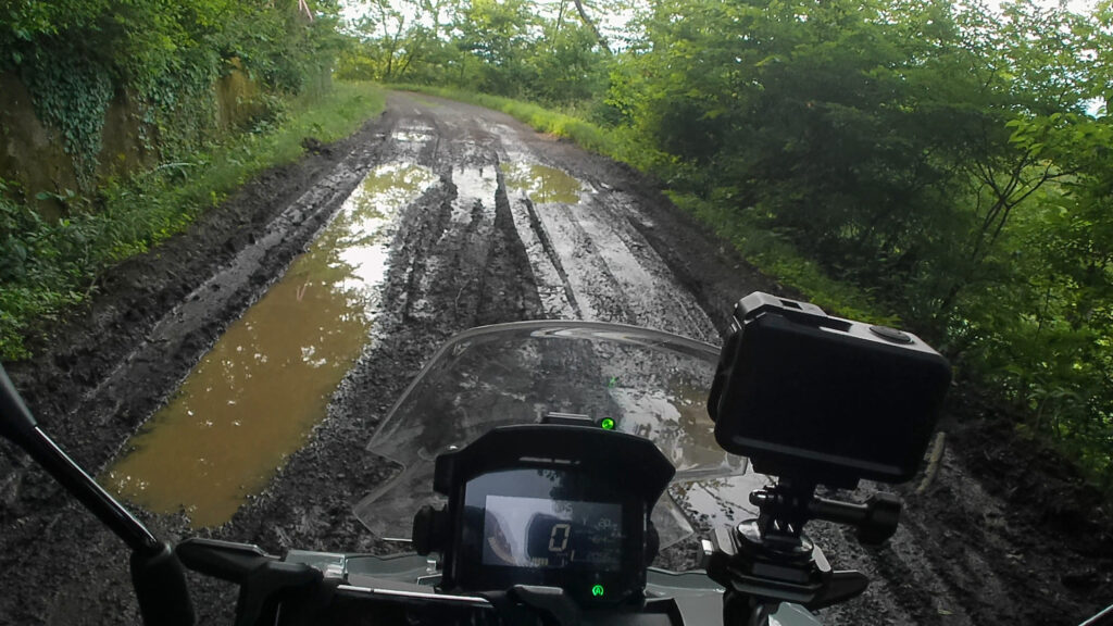 深い轍と大きな水たまりが続く山中の泥濘路