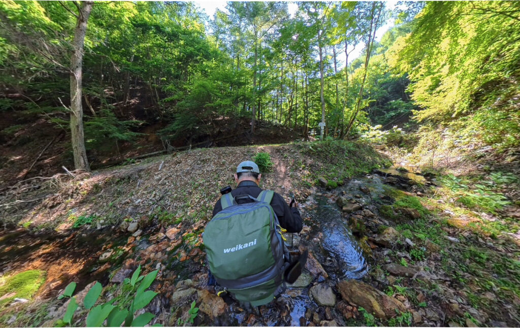 日本一海から遠い地点へ向かう登山道で沢を渡るShin