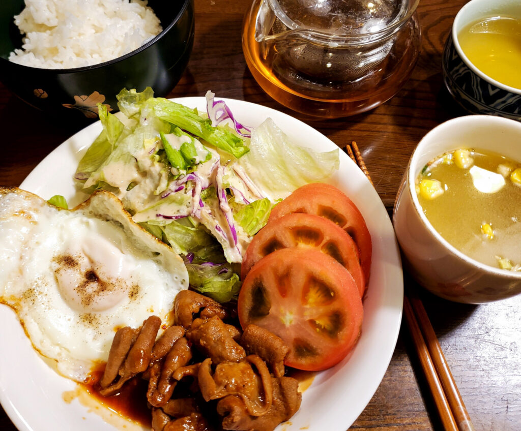 松屋の牛ホルモン焼きに、目玉焼き、レタスのサラダ、トマトを添えた盛り付け例。