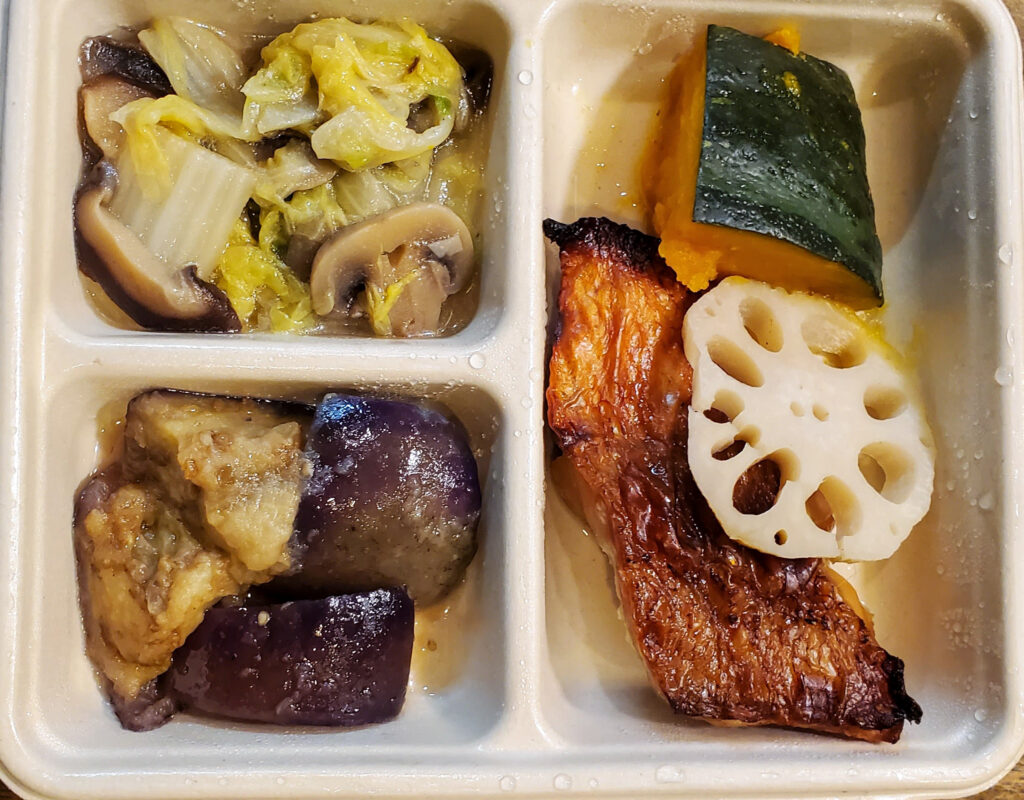 DELIPICKSの赤魚醤油漬け焼き。白い3区画のトレーに焼き魚、カボチャとレンコン、ナス、白菜とキノコの副菜が盛り付けられている。