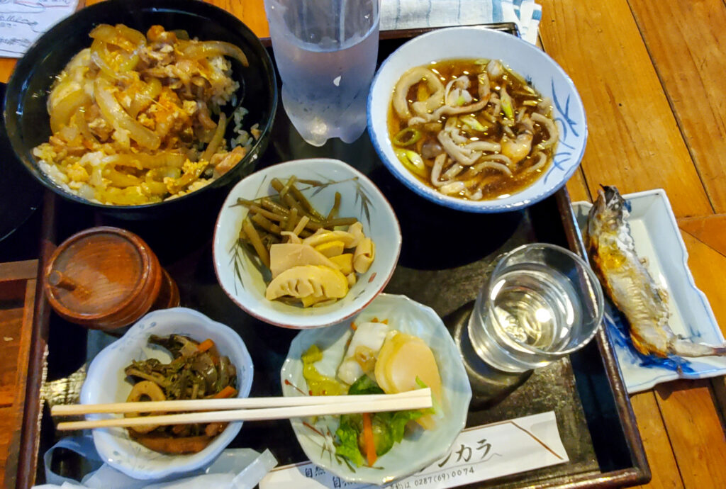 テンカラでいただいた親子丼と汁物、山菜の小鉢、漬物、川魚の塩焼きが並ぶ食卓。