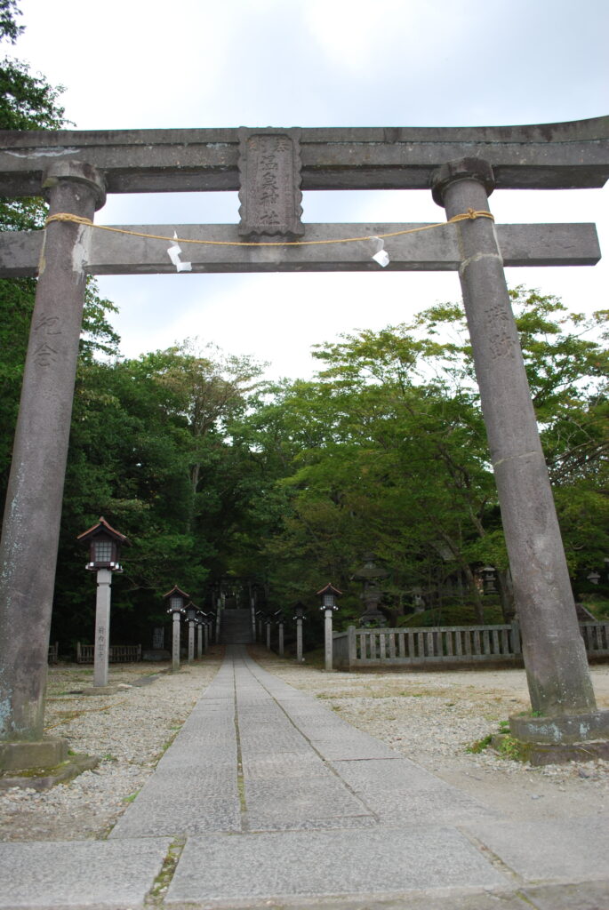 那須温泉神社の石鳥居と、石灯籠が並ぶ木々に囲まれた参道。