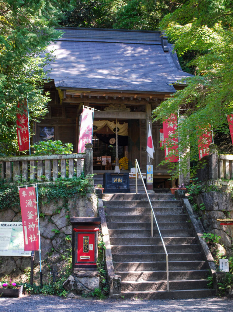 出流原弁天池のほとりにある涌釜神社。石段の先に木造の社殿が建ち、周囲を緑に囲まれている。