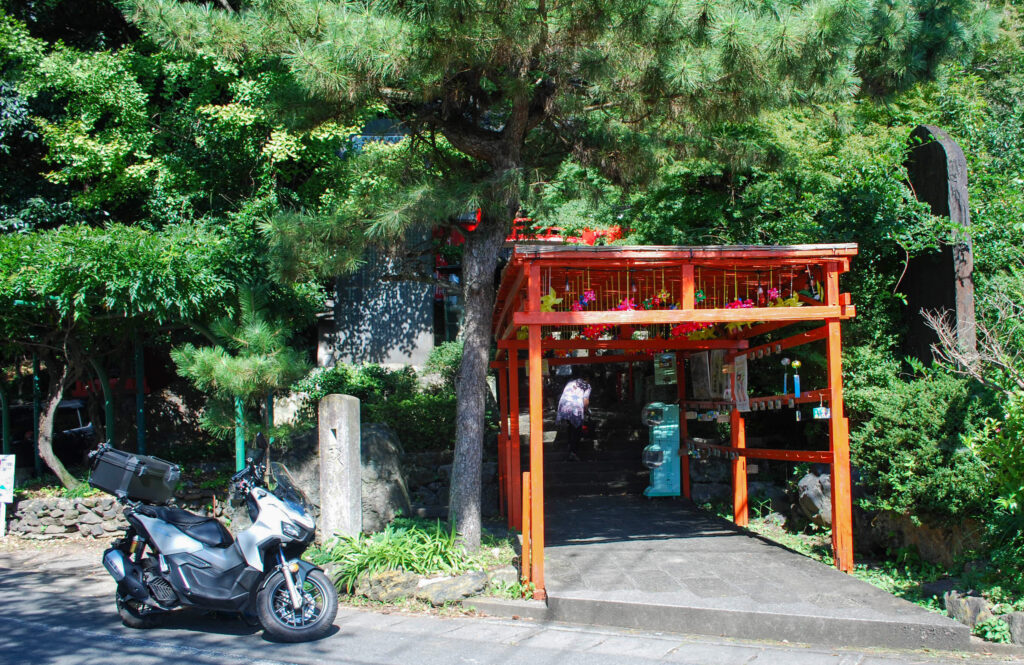 磯山弁財天の参道入口。朱色の屋根付き通路の前に白いADV160が停められている。